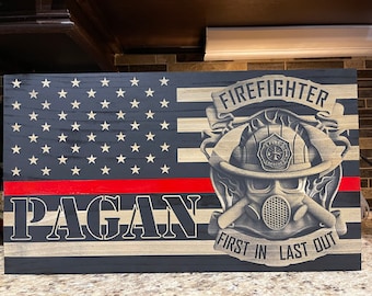 May include: Wooden American flag design with a red stripe and the name "PAGAN". It features a firefighter's helmet and gas mask graphic, with the words "FIREFIGHTER" and "FIRST IN LAST OUT".
