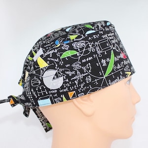 May include: Black surgical scrub cap with a white mathematical formula print and colourful accents. The cap is tied at the back and designed to cover the head. The fabric has a dark background with white, green, yellow, and orange shapes and symbols.