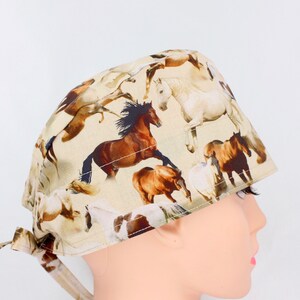 Peut inclure: Un bonnet de chirurgien beige avec un motif répété de chevaux dans des tons de marron, beige et blanc. Les chevaux sont représentés dans des poses dynamiques, certains se cabrant ou galopant. Le bonnet a des liens pour un ajustement sûr.