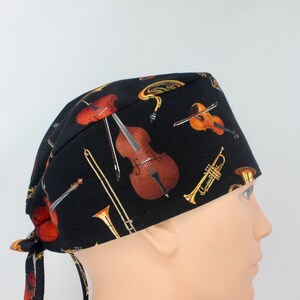 Può includere: Cappello da lavoro nero con stampa di strumenti musicali. Il cappello presenta un violoncello, violini, trombe e tromboni.