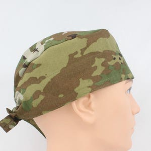 May include: Camouflage patterned head covering in shades of green, brown, and tan. The headwear is tied at the back and is designed to fit snugly. This item is suitable for various outdoor activities or as a fashion accessory.