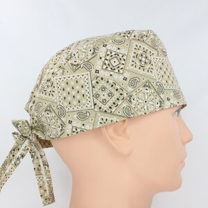 Peut inclure: Un bonnet de chirurgien à motif bandana beige et noir avec une cravate à l'arrière.