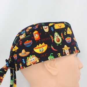 Può includere: Cappello chirurgico nero con un motivo festivo e colorato. Il design presenta illustrazioni di cartoni animati di tacos, avocado, peperoncini e altri alimenti messicani. La parola "Fiesta" è stampata sul cappello.