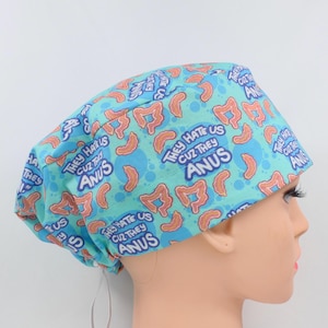 May include: A light blue surgical scrub cap with a repeating pattern of brown intestines and the text "THEY HATE US CUZ THEY ANUS" in a circular design. The cap is made of a soft, lightweight fabric.