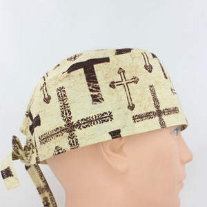 Peut inclure: Un bonnet de chirurgien beige avec un motif de croix brun. Le bonnet a une attache sur le côté.