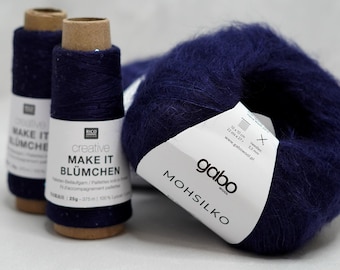May include: An image of navy blue yarn and spools of thread. Two spools of navy blue thread are labeled "creative MAKE IT BLÜMCHEN". A large ball of navy blue yarn is labeled "gabo MOHSILKO". The yarn is fluffy and soft, perfect for knitting and crochet projects.