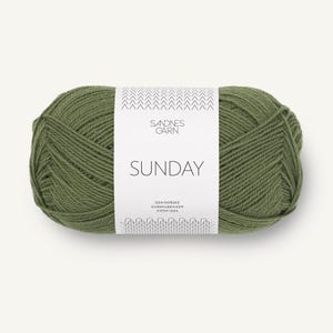 Può includere: Un gomitolo di filato verde oliva avvolto in un'etichetta di carta bianca. L'etichetta riporta il testo Sandnes Garn, Sunday e Den Norske Garnfabrikken Siden 1888, con un motivo a chevron in alto e un motivo a maglia in basso.