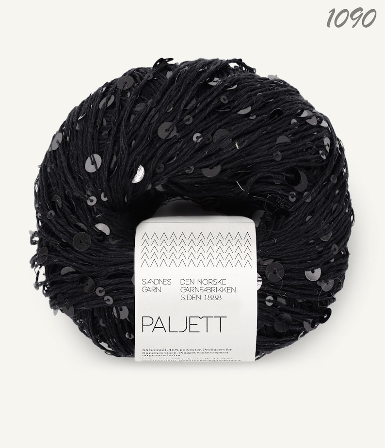 May include: A round ball of black yarn embellished with small, shiny black sequins. A white paper label is wrapped around the center, featuring the text Sandnes Garn, Den Norske Garnfabrikken Siden 1888, Paljett, and the number 1090 at the top.