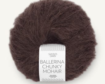May include: A round ball of dark brown, fuzzy mohair yarn with a white paper label wrapped around the center. The label features the text Sandnes Garn, Ballerina Chunky Mohair, and Den Norske Garnfabrikken Siden 1888 with a chevron pattern.