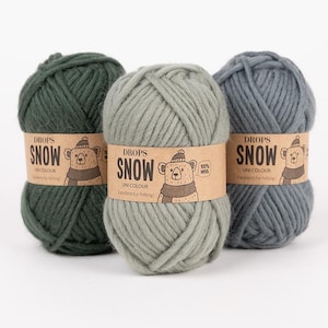 May include: Three skeins of Drops Snow yarn in dark green, light sage green, and slate blue. Each ball features a tan paper label with a bear illustration, the text Drops Snow, Uni Colour, 100% Wool, and the phrase Excellent for felting.