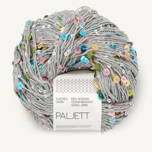 May include: A ball of light gray yarn interwoven with small, round, multicolored sequins in shades of blue, pink, green, and gold. A white paper label wraps around the center, featuring the text 1121, SANDNES GARN, and PALJETT.