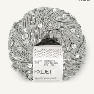 May include: A ball of light gray yarn interwoven with small, reflective silver sequins. A white paper label wraps around the center, featuring the text Sandnes Garn, Den Norske Garnfabrikken Siden 1888, Paljett, and the number 1120 at the top.