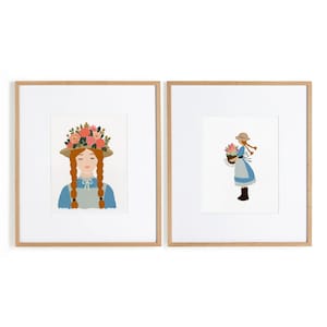 May include: Two framed art prints featuring a character with red braided hair wearing a straw hat and blue dress. The left print shows a close-up with a floral crown, while the right print shows a full-body view holding a basket of flowers.