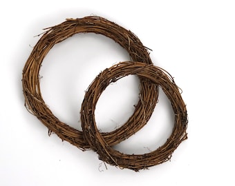 May include: Two brown twig wreaths, one larger than the other, are nested together. The wreaths are made of natural twigs and are perfect for crafting.