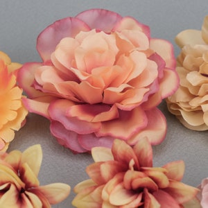 May include: Close-up of several artificial flowers in shades of peach, pink, and yellow. The central flower is a large, multi-layered bloom with a gradient of colors. Other flowers are visible, showcasing different petal arrangements.
