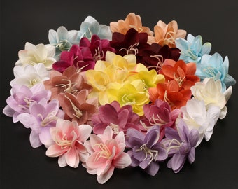 Op de afbeelding: Een verzameling van 24 kunstbloemen in verschillende kleuren, waaronder roze, paars, geel, oranje, rood en wit. De bloemen zijn in een cirkel gerangschikt en hebben een delicate, gelaagde uitstraling.