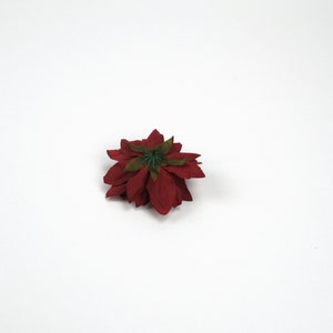 May include: A single red poinsettia flower with a green centre, isolated against a white background.