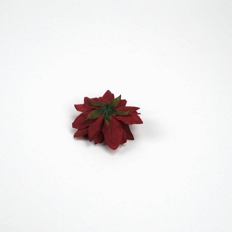 May include: A single red poinsettia flower with a green centre, isolated against a white background.