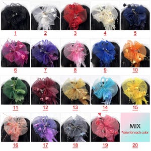 Op de afbeelding: Een verzameling van twintig haaraccessoires in verschillende kleuren, waaronder zwart, wit, rood en blauw. Elk accessoire heeft een decoratief ontwerp met stof, veren en kralen, bevestigd aan een haarclip. De afbeelding bevat een mix van kleuren.