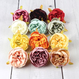 May include: Assortment of 12 artificial flower heads in various colors and styles, including peach, yellow, orange, red, burgundy, and green. The flowers are made of fabric and have a realistic appearance.