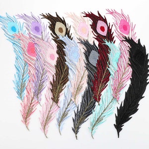 May include: Assortment of ten colorful peacock feather embroidery patches. The patches are made of fabric and have a detailed embroidered design. The feathers are in various colors, including blue, pink, purple, and black.