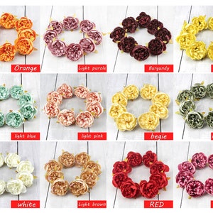May include: Assortment of 12 artificial flower wreaths in various colors, including orange, light purple, burgundy, light yellow, light blue, light pink, beige, light green, white, light brown, red, and deep pink. Each wreath is made of small, fabric flowers.