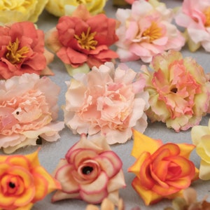 May include: Assortment of artificial flowers in various colors, including peach, orange, yellow, and pink. The flowers have multiple layers of petals and are arranged closely together. Some flowers have yellow centers.