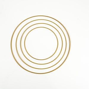 Könnte beinhalten: Vier konzentrische goldene Metallreifen, die in einem Kreis angeordnet sind, auf weißem Hintergrund.