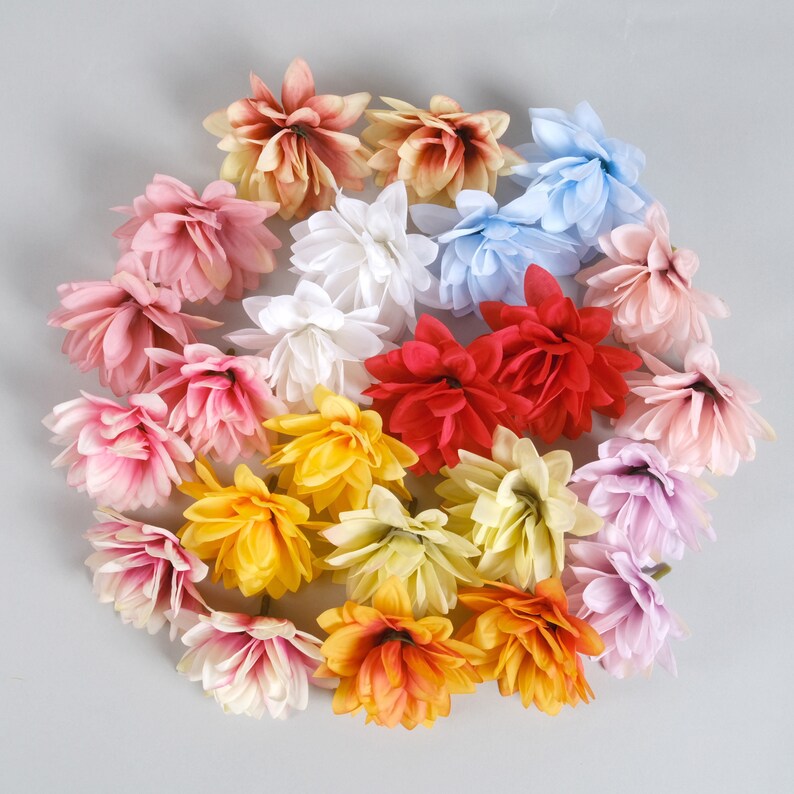 Puede incluir: Una colecci&oacute;n de 18 cabezas de flores artificiales en varios colores, incluyendo rosa, amarillo, naranja, rojo, blanco y azul. Las flores est&aacute;n dispuestas en c&iacute;rculo y tienen un aspecto en capas y con volantes.