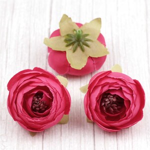 May include: Three artificial flowers, two are pink and one is a light green with a pink centre. The pink flowers have a ruffled appearance.