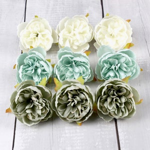 May include: Nine artificial flowers in various shades of green and white. The flowers are arranged in three rows of three. The flowers are all closed and have a ruffled appearance.