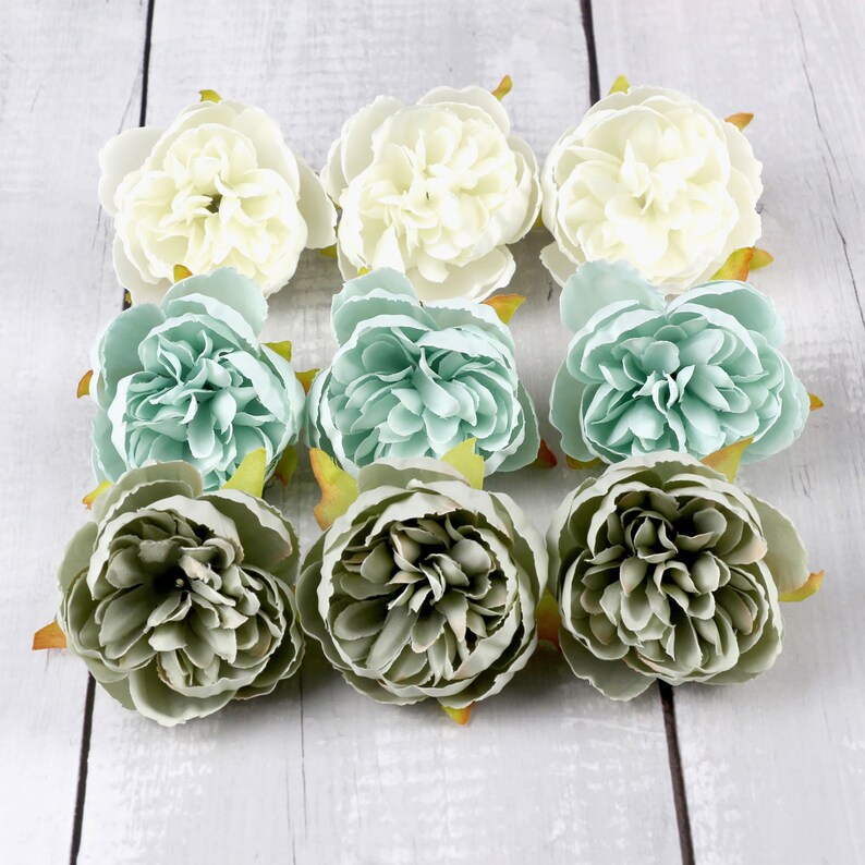 May include: Nine artificial flowers in various shades of green and white. The flowers are arranged in three rows of three. The flowers are all closed and have a ruffled appearance.