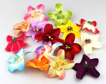 Op de afbeelding: Assortiment van 14 kunstbloemen in verschillende kleuren, waaronder rood, roze, paars, blauw, geel, oranje en groen. De bloemen zijn gemaakt van stof en hebben een realistisch uiterlijk.