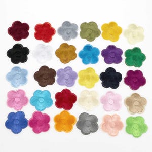 Pode incluir: Uma coleção de patches de flores bordadas em várias cores, incluindo vermelho, amarelo, azul e verde. Os patches estão dispostos em um padrão de grade, mostrando seus designs detalhados de pétalas. Estes patches são adequados para embelezar tecidos.