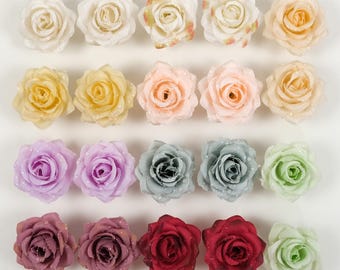 Puede incluir: Surtido de 20 cabezas de flores de rosa artificiales en varios colores, incluyendo blanco, crema, melocotón, lavanda, gris, verde, rojo y burdeos. Las flores están dispuestas en filas sobre un fondo blanco.