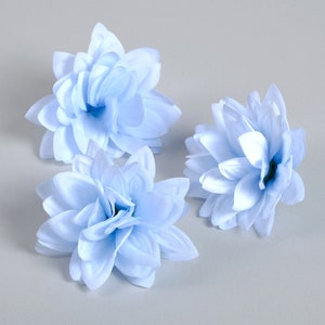 Puede incluir: Tres flores artificiales de color azul claro con m&uacute;ltiples capas de p&eacute;talos.