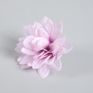 Puede incluir: Una sola flor artificial de color lila claro con m&uacute;ltiples capas de p&eacute;talos.