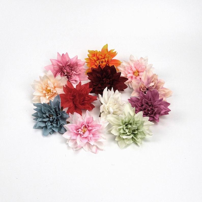 May include: Assortment of 10 artificial dahlia flowers in various colours, including pink, red, white, green, and blue. The flowers are made of fabric and have a realistic appearance.