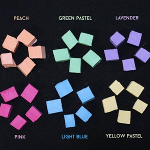 May include: Assortment of pastel chalk in various colors, including peach, green pastel, lavender, pink, light blue, and yellow pastel. Each color is arranged in a circle shape.