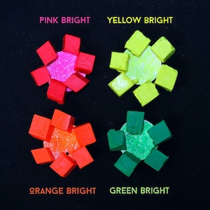 May include: Four sets of colorful, square-shaped blocks arranged in a flower pattern. Each set is a different color: pink, yellow, orange, and green. The blocks are arranged in a circle around a small, round, white disc. The text "PINK BRIGHT", "YELLOW BRIGHT", "ORANGE BRIGHT", and "GREEN BRIGHT" is written below each set of blocks.