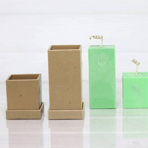 May include: Three candle molds, two are brown and one is green. The brown molds have a base and are square shaped. The green mold is square shaped and has a wick.