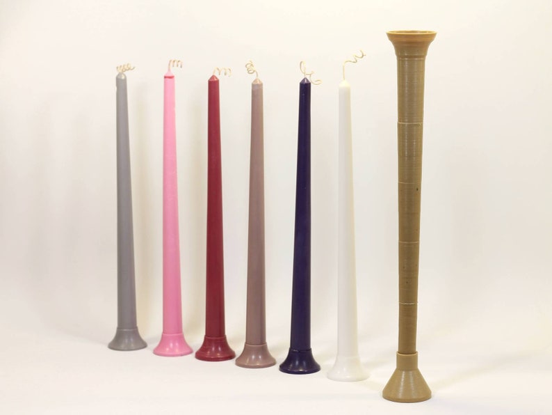 May include: Eight tall candles in various colors, including gray, pink, red, beige, and purple, with white and a brown candle holder.