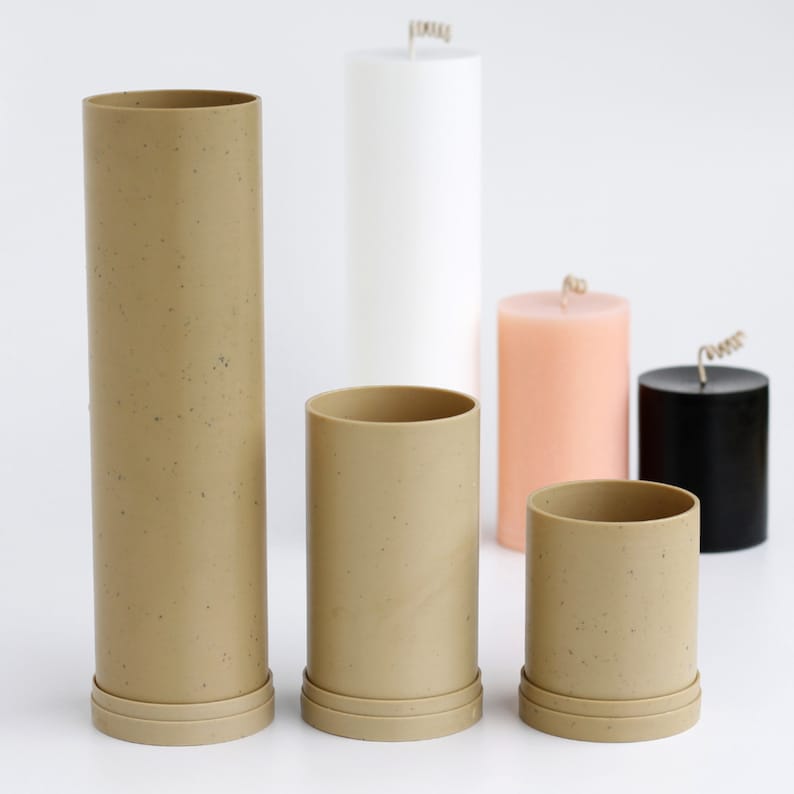 May include: Five candle molds in various sizes. The molds are made of a speckled brown material and have a smooth, cylindrical shape. The molds are arranged in a row on a white surface.
