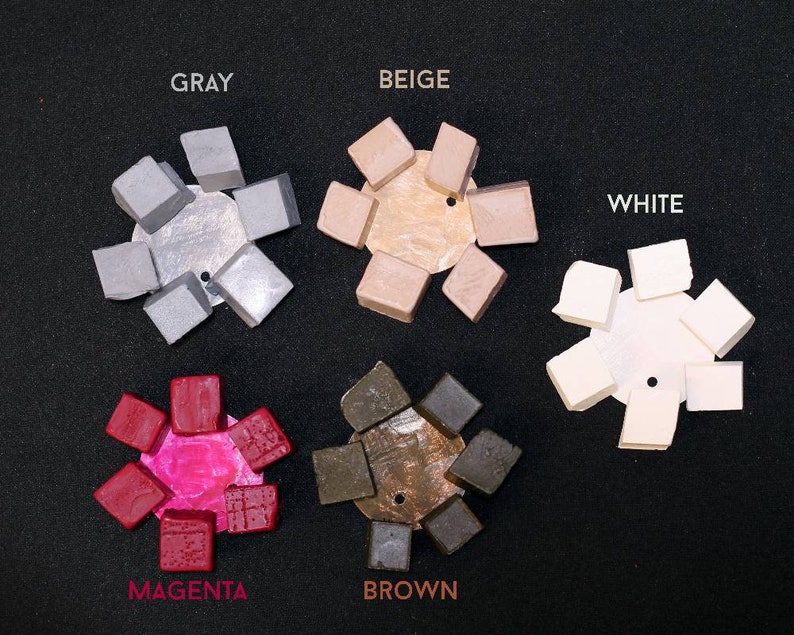 May include: A set of eight color swatches in the colors gray, beige, white, magenta, and brown. Each swatch is a small square with a textured surface.