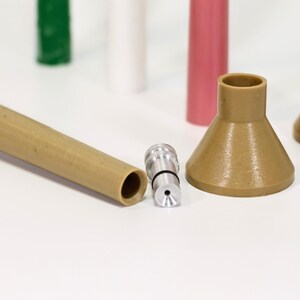 May include: A close-up of a brown plastic funnel with a silver nozzle attached to a brown plastic tube. The funnel is sitting on a white surface.