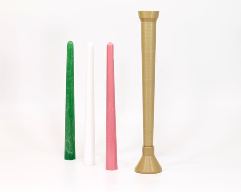 May include: Three taper candles in green, white, and pink, standing next to a brown candle holder.