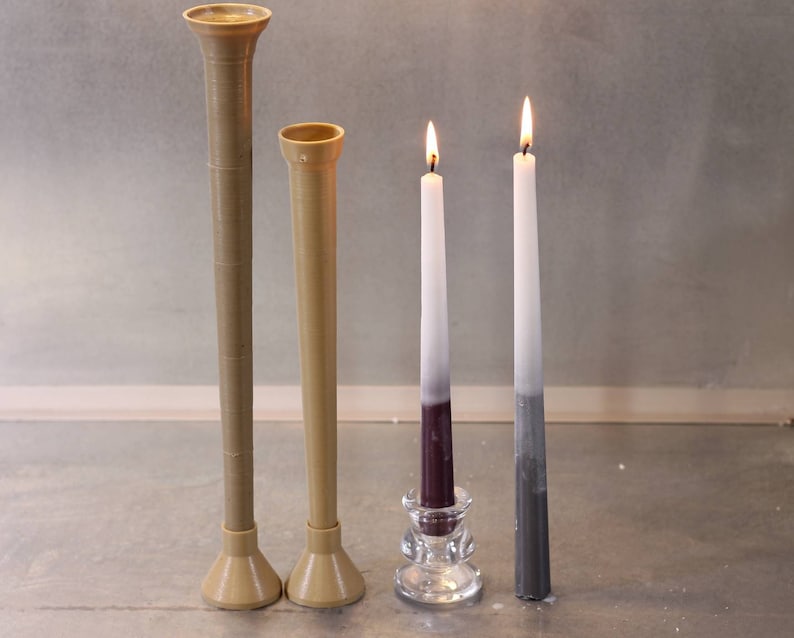 May include: Two brown ceramic candle holders, one taller than the other, and two candles in a glass holder. The candles are white with a purple and gray gradient.