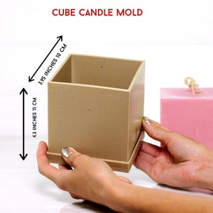 Könnte beinhalten: Eine beige quadratische Kerzenform mit einer Größe von 11 cm x 10 cm. Die Form ist aus Silikon und hat eine glatte Oberfläche.