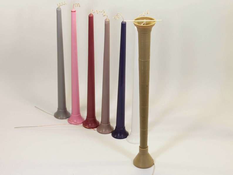 May include: A set of eight tall, slender candles in various colors, including gray, pink, red, purple, and white. The candles have a decorative base and a curled wick.