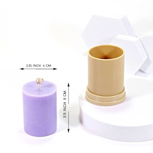 Puede incluir: Una vela morada con una mecha dorada en un molde de plástico transparente. El molde mide 8 cm de alto y 6 cm de ancho. La vela mide 8 cm de alto y 6 cm de ancho.